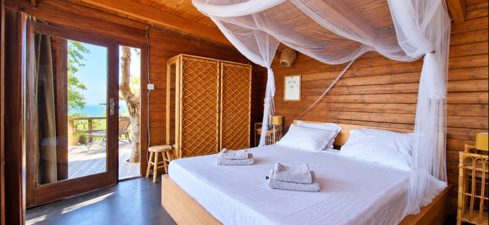 Lit à baldaquin avec moustiquaire dans la cabane La Cahute, île du Levant