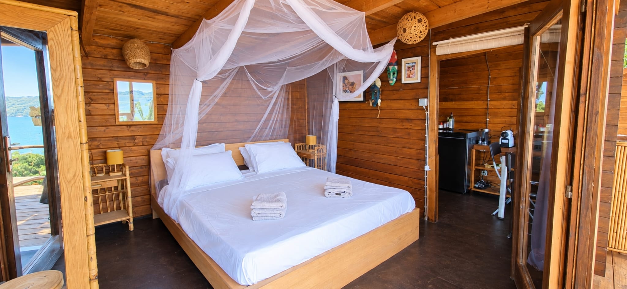 Chambre en bois de La Cahute avec lit à baldaquin et coin café
