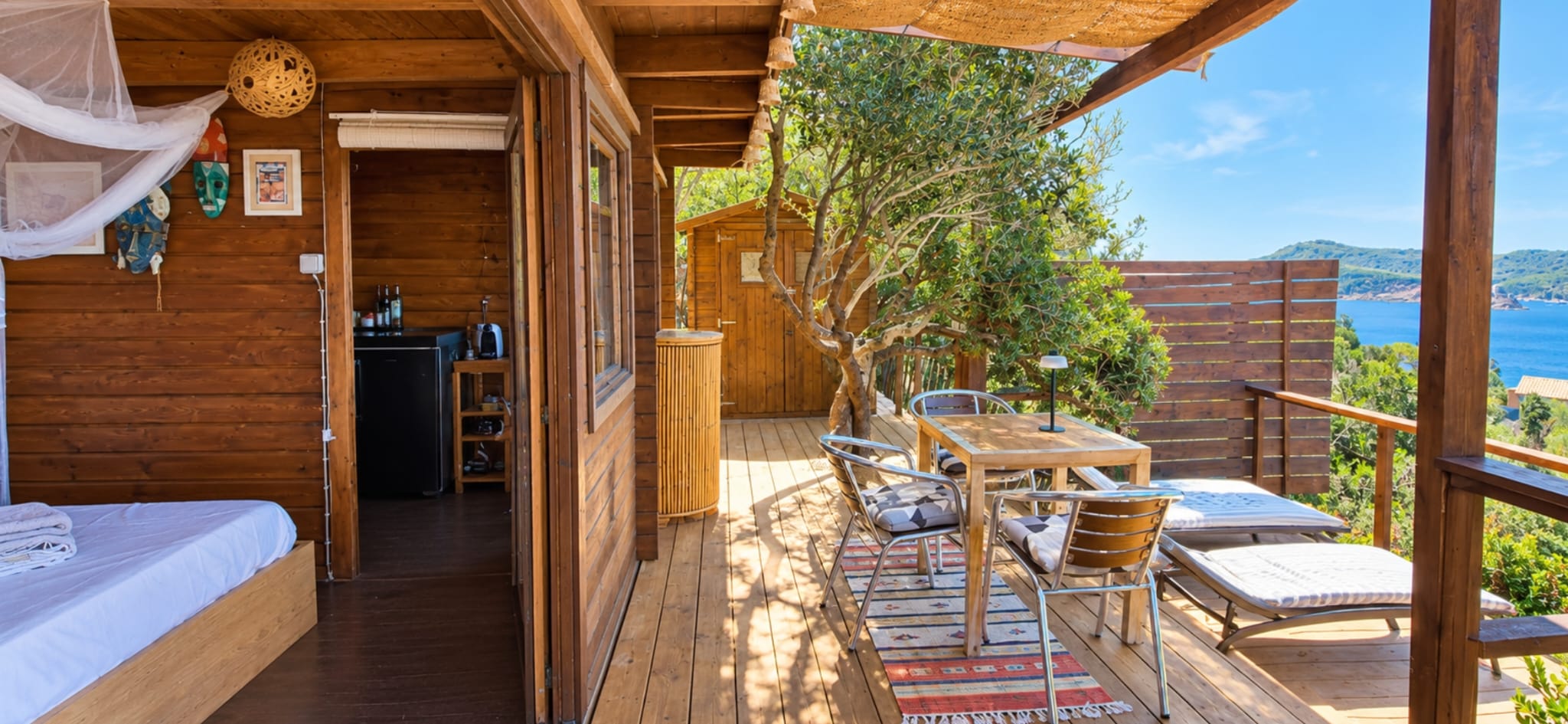 Terrasse de La Cahute avec transats sous l'olivier, vue sur la Méditerranée